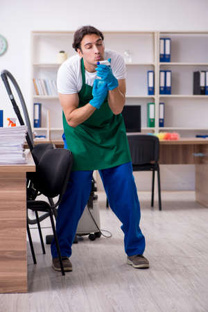 Young handsome contractor cleaning the officeの写真素材