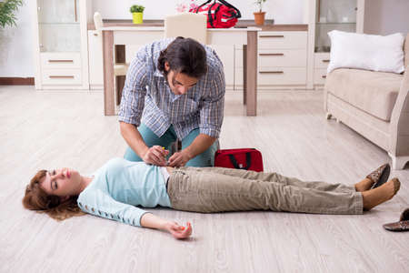 Young couple in first aid concept at homeの写真素材