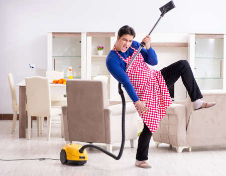 Young man vacuum cleaning his apartmentの写真素材