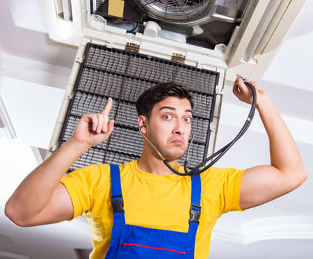 Repairman repairing ceiling air conditioning unitの写真素材