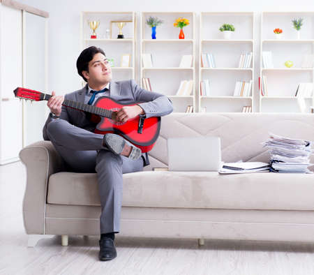 Businessman playing guitar at homeの写真素材