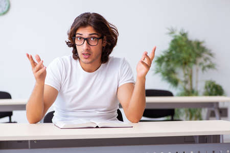 Young male student sitting in the classroomの写真素材