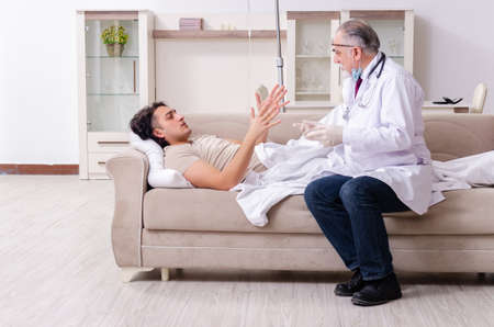 Old male doctor visiting young male patientの写真素材