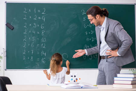 Teacher with young girl in the classroomの写真素材