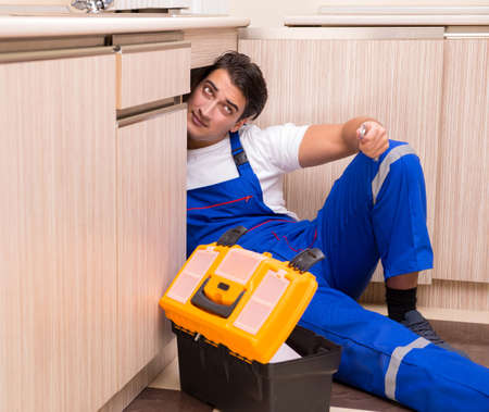 Young repairman working at the kitchenの写真素材