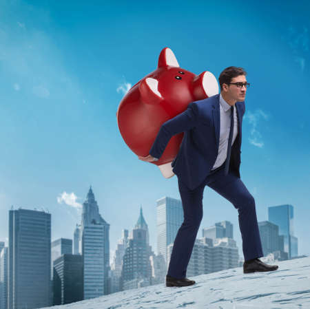 Businessman carrying the piggybank with savingsの写真素材