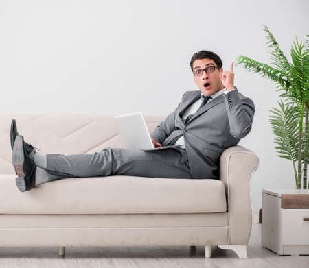 Young businessman lying on the sofaの写真素材