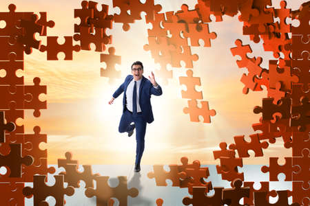 Businessman breaking the wall of jigsaw puzzleの写真素材