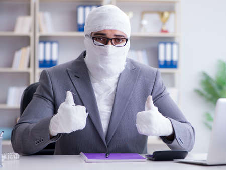 Bandaged businessman worker working in the office doing paperworの写真素材