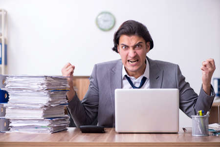 Young male employee unhappy with excessive workの写真素材