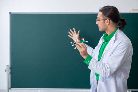 Young male chemist teacher in front of blackboardの写真素材