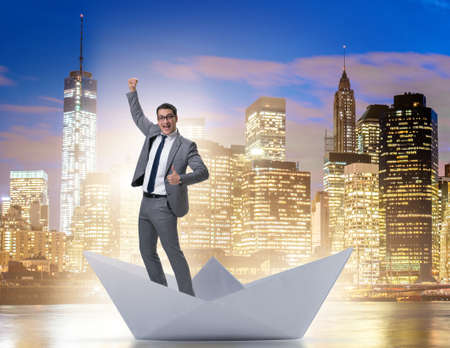 Excited businessman riding paper ship boatの写真素材