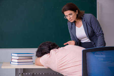 Old female teacher and male student in the classroomの写真素材