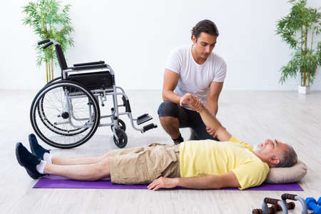 Old injured man doing exercises indoorsの写真素材