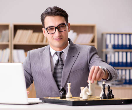 Young businessman playing chess in the officeの写真素材