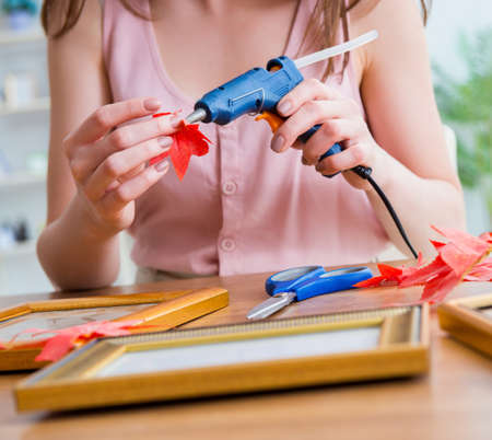 Woman decorating picture frame in scrapbooking conceptの写真素材