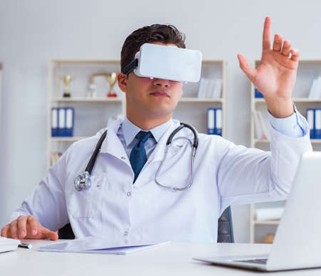 Young doctor with vr virtual reality headset working in the officeの写真素材