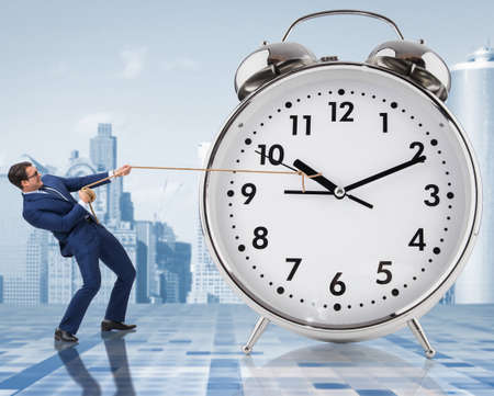 Businessman pulling clock in time management conceptの写真素材