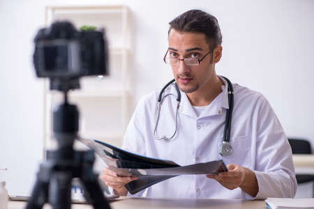 Young male doctor radiologist recording video for his blogの写真素材