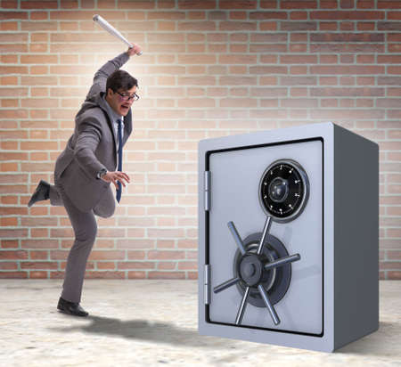 Angry man with baseball bat hitting money safeの写真素材