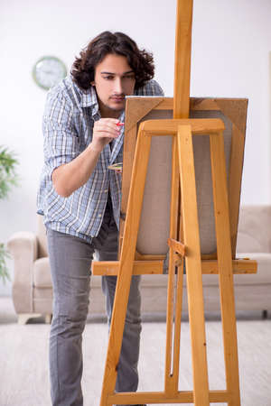 Young handsome man enjoying painting at homeの写真素材