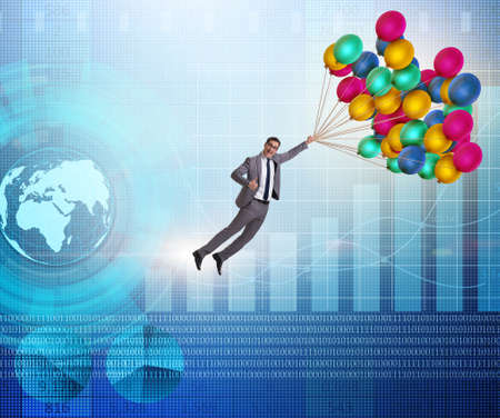 The businessman flying on balloons over graphの写真素材