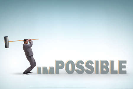 Businessman hitting the word impossible with hammerの写真素材