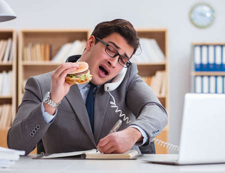 Hungry funny businessman eating junk food sandwichの写真素材