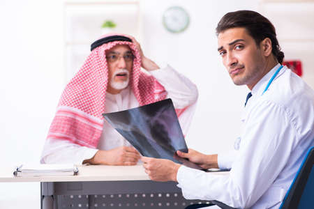 Old male arab visiting young male doctorの写真素材