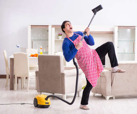 Young man vacuum cleaning his apartmentの写真素材
