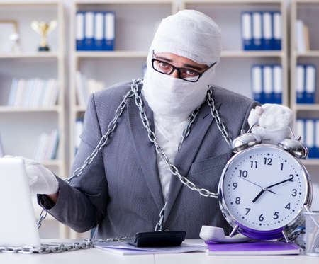 Bandaged businessman worker working in the office doing paperworkの写真素材