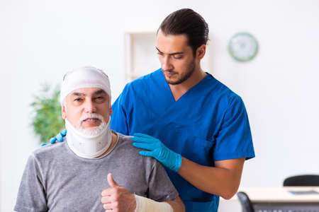 Young male doctor and old patient in first aid conceptの写真素材