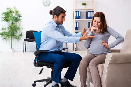 Pregnant woman visiting young male psychologistの写真素材