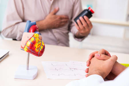 Old man visiting young male doctor cardiologistの写真素材