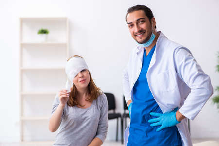 Young head injured woman visiting young male doctorの写真素材