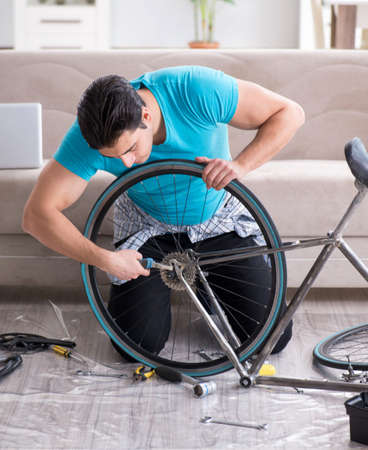 The young man repairing bicycle at homeの写真素材