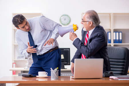 Old boss and young male employee in the officeの写真素材