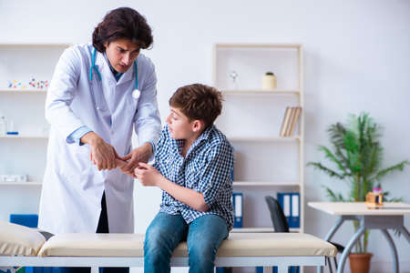 Hand injured boy visiting young male doctorの写真素材