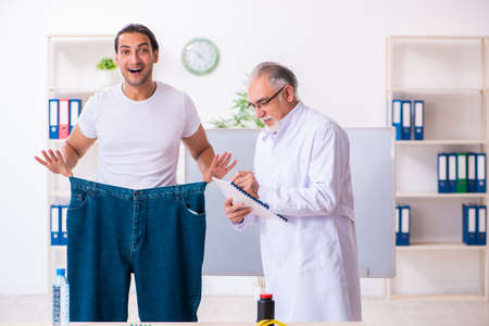 Doctor dietician and happy patient wearing large trousersの写真素材