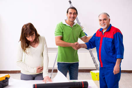 Young couple and old contractor in home renovation conceptの写真素材