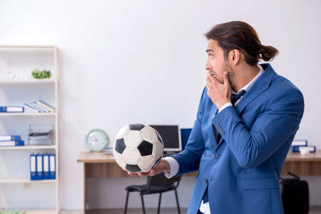 Young male employee playing football in the officeの写真素材