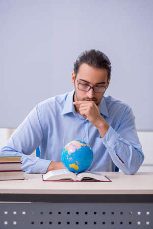 Young male geography teacher in front of whiteboardの写真素材