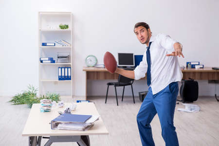 Young male employee throwing rugby ball in the officeの写真素材