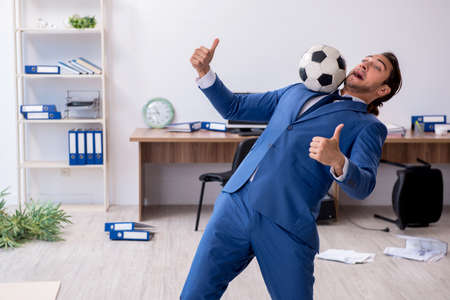 Young male employee playing football in the officeの写真素材