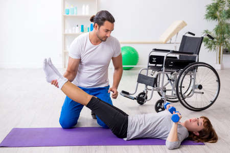 Woman in wheel-chair doing sport exercises with personal coach