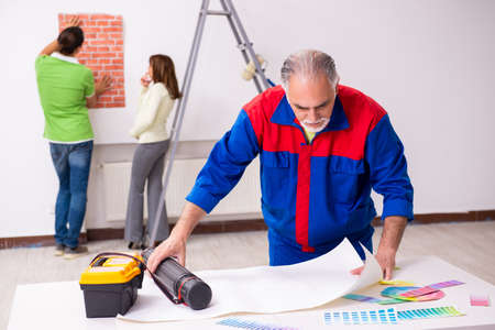 Young couple and old contractor in home renovation concept