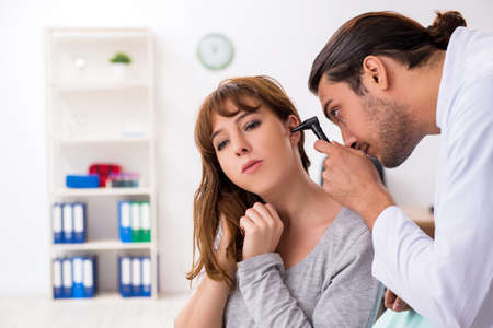 Young woman visting young male doctor otorhinolaryngologistの写真素材