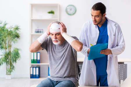 Young male doctor and old patient in first aid conceptの写真素材