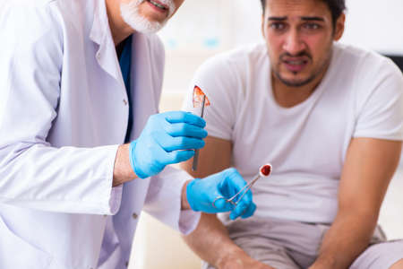 Leg injured man visiting old doctor in first aid concept