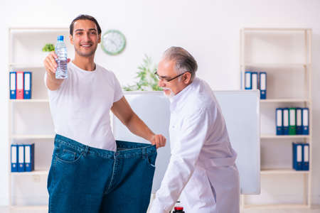 Doctor dietician and happy patient wearing large trousersの写真素材